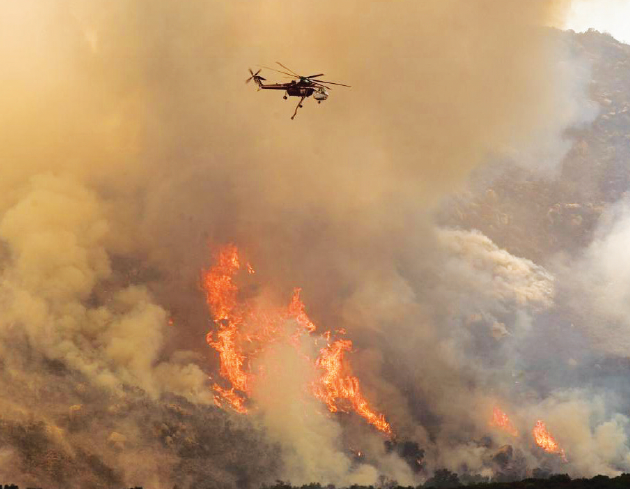 a helicopter flying over a wildfire