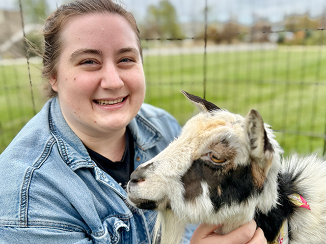 A vet student petting a goat.