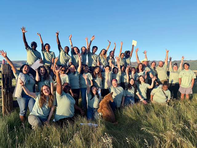 A group of students posing outside in evening light.